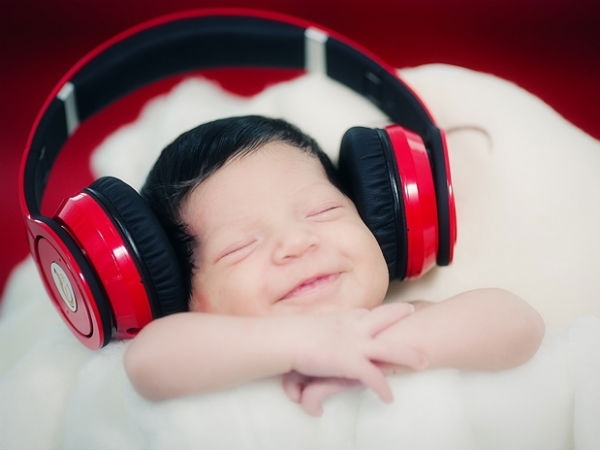 Обои Улыбающийся малыш с закрытыми глазами слушает музыку через